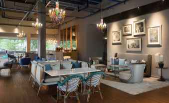 a modern living room with a large dining table , chairs , and paintings on the wall at Delonix Hotel Karawang