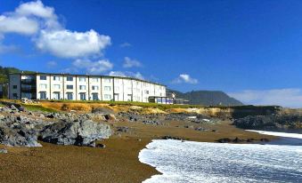 a large building on a hill overlooking the ocean , with a sandy beach in front of it at Adobe Resort