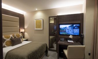 a modern hotel room with a comfortable bed , desk , and flat screen tv , along with a view of a cityscape at The Kings Head Hotel
