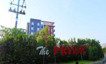 "a large red sign that says "" the pride "" is in front of a building and is surrounded by greenery" at The Pride