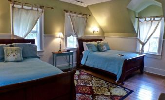 a room with two beds , one on each side of the room , and a rug covering the floor at Magnolia Inn