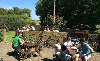 a group of people sitting around a picnic table with bicycles parked nearby , enjoying each other 's company at The Farm Burscough