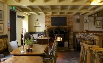 a cozy restaurant with a wooden dining table , chairs , and a fireplace , creating an inviting atmosphere at The Welldiggers Arms