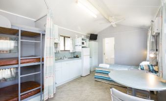 a kitchen with a refrigerator , sink , and cabinets is shown next to a dining area at Big4 Townsville Gateway Holiday Park