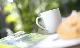 A cup and saucer are placed on the table alongside an open white plate at iclub To Kwa Wan Hotel