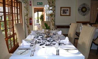 a dining room with a table set for a formal dinner , complete with white plates , silverware , and wine glasses at Hole in One