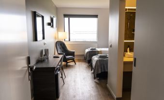 a hotel room with two beds , a desk , and a chair , all situated next to each other at Black Beach Guesthouse