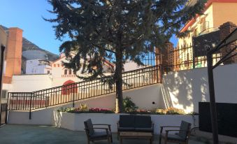 a large tree stands in front of a white building with an outdoor seating area at Hotel Balneario de Graena