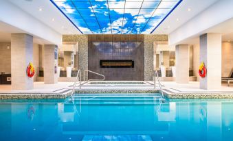 a large indoor pool with a blue sky ceiling and marble walls , featuring two handrails at Delta Hotels by Marriott Waterloo