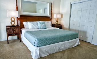 a large bed with a white and blue comforter is situated in a room with a mirror on the wall at Coral Reef at Key Biscayne