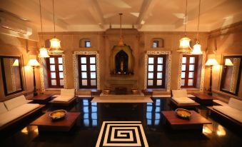 a room with a black floor and white and gold squares on the floor , as well as chandeliers hanging from the ceiling at Guleria Kothi at Ganges