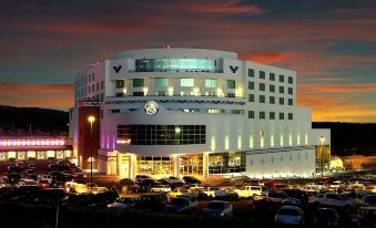 a large , modern building with a distinctive design is surrounded by cars in the evening at Gold Country Casino Resort