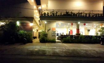 a house with a balcony and people sitting at tables in the front yard at night at Sacca Residence & Resto