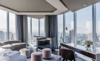 a modern living room with large windows , gray carpet , and comfortable furniture , offering a view of the city at Icon Hotel