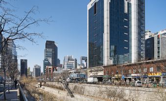 There is a view of buildings and water from the street, with people walking on it at Hotel Venue-G Seoul