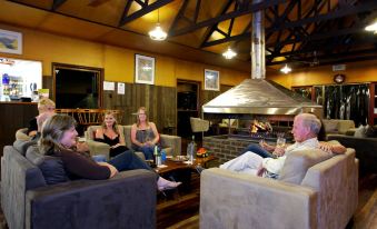 a group of four people sitting in a living room , enjoying each other 's company and drinking wine at Broken River Mountain Resort