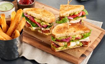 a wooden cutting board with three sandwiches placed on it , accompanied by a variety of bread and condiments at Courtyard Rome Riverwalk