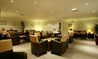 a well - lit lounge area with several chairs and couches , where several people are sitting and relaxing at Holiday Inn Leeds - Wakefield M1, Jct.40