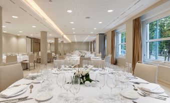 a well - decorated banquet hall with numerous tables and chairs arranged for a formal event , possibly a wedding reception at NH Madrid Nacional