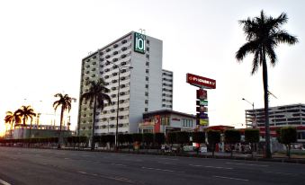 "a tall building with a green "" gemini "" sign on top is surrounded by palm trees and other buildings" at Hotel 101 Manila