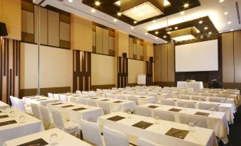 a large conference room with white tables and chairs , a projector screen , and multiple speakers at Kantary Hotel Kabinburi