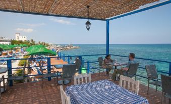 a man and a woman are sitting on a patio overlooking the ocean , enjoying their time together at Manolya Hotel