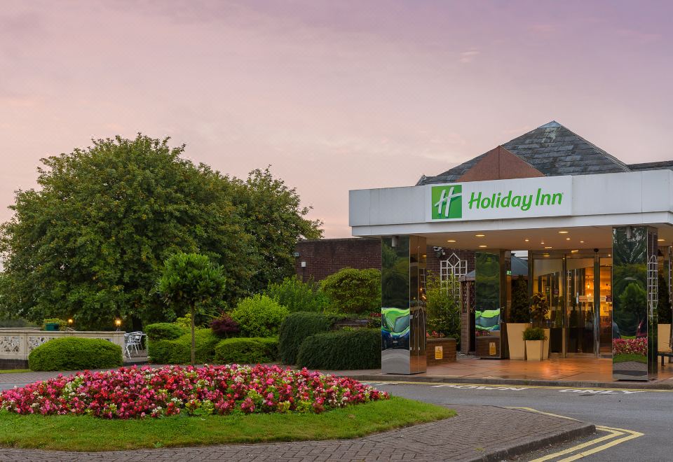 an exterior view of a holiday inn express hotel , with a large parking lot in front of it at Holiday Inn Leeds - Garforth