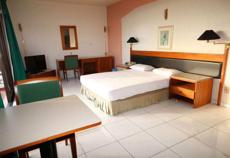 a clean and well - organized hotel room with a double bed , a desk , a chair , and a television at Taj Mahal Hotel