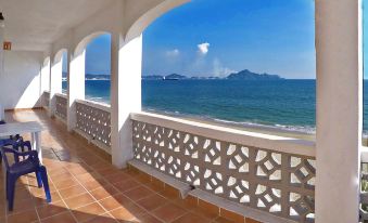 a beautiful view of the ocean through an arched balcony , with clear blue skies and white sandy beaches in the distance at Hotel Marbella