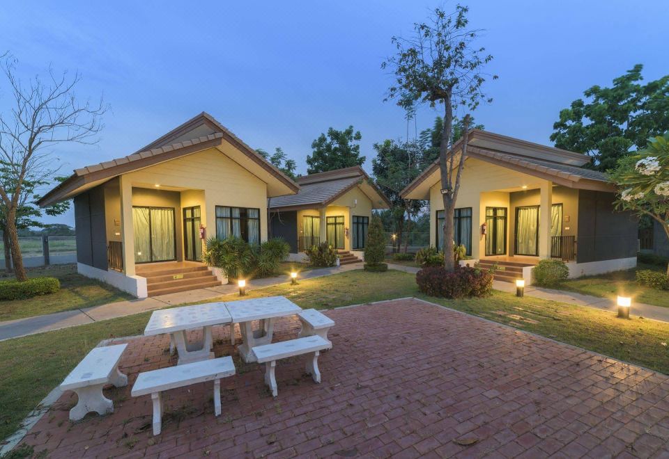 a group of small wooden cabins situated in a grassy field , with picnic tables nearby at Chanalai Resort and Hotel