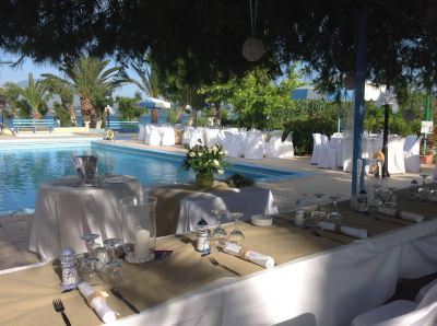 a large outdoor dining area with tables set up for a party , surrounded by trees and a swimming pool at Hotel Summery