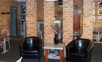 a brick wall with two black leather chairs and a small table in front of them at The Crossing Motel
