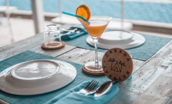 a dining table with a wine glass , a plate of cookies , and a cocktail glass at Cabana Retreat - Glamping