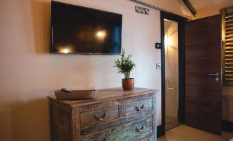 a room with a large flat - screen tv mounted on the wall , a wooden dresser , and a door leading to another room at Charter House