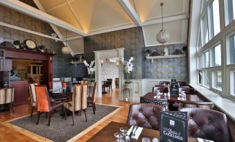 a large , elegant dining room with multiple tables and chairs arranged for a group of people to enjoy a meal together at Clanard Court Hotel