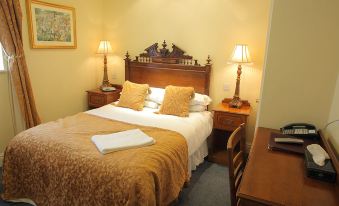 a large bed with a wooden headboard and white linens is in a hotel room at The Atherstone Red Lion Hotel