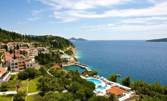 a beautiful view of the sea and coastline , with a large pool surrounded by lush greenery at Sun Gardens Dubrovnik