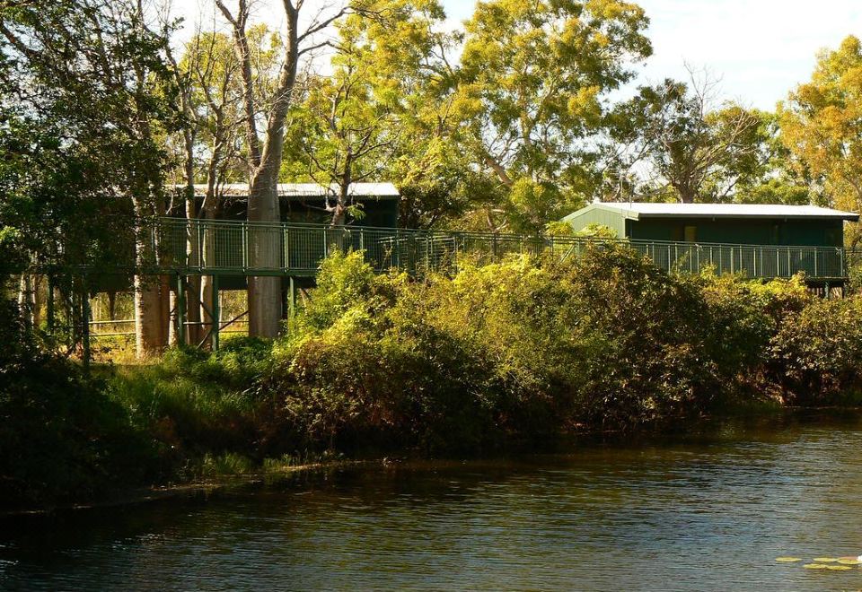 a forested area with a river running through it , where a bridge and several houses are visible at Parry Creek Farm Tourist Resort & Caravan Park