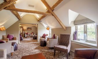 a room with wooden beams on the ceiling and various seating options including chairs and tables at Wild Thyme & Honey