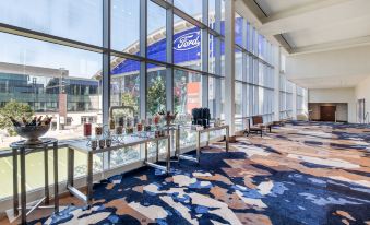 a large , open room with a blue and gray patterned carpet , large windows , and various seating arrangements at Omni Frisco-Dallas Hotel at the Star