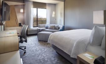 a hotel room with a bed , couch , and desk , along with a window and a view of the outside at Courtyard LaGrange