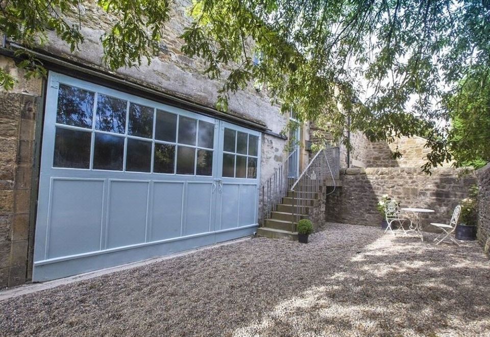 a stone house with a blue garage door and stairs leading up to the front at The Stables