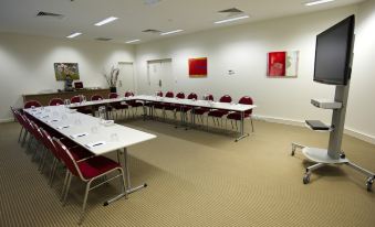a conference room with a long table and chairs arranged in a semicircle , creating an open and spacious area at Quest Mawson Lakes