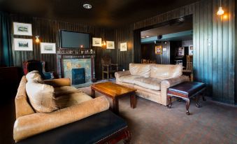 a cozy living room with a leather couch , a wooden coffee table , and a flat - screen tv mounted on the wall at Holiday Inn Aberdeen - West