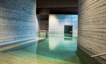 a modern building with a large indoor pool surrounded by concrete walls , creating a minimalist and serene atmosphere at Yasuragi