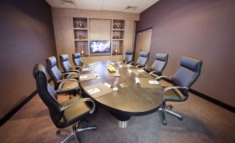 a conference room with a large wooden table surrounded by chairs and a flat screen tv on the wall at Van der Valk Hotel Middelburg