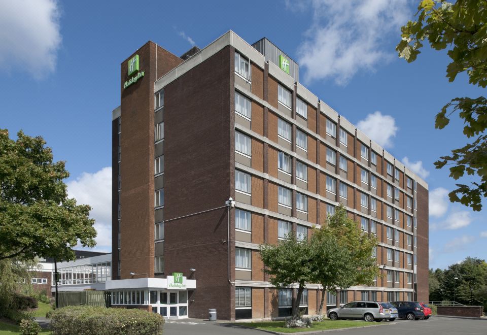 a large brick building with a green sign on the side , located in a city setting at Holiday Inn Washington