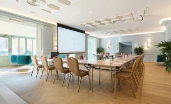 a conference room with a large table , chairs , and a projector screen in the background at Hob le Cheval Blanc