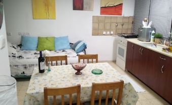 a small living room with a dining table , chairs , and a couch in the background at Like Home Gedera