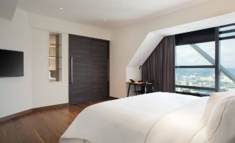 A modern bedroom features large windows, a white bed in the center, and an open layout at Element Kuala Lumpur